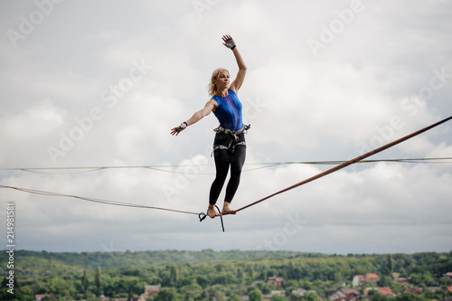 Young woman balancing tilted her hands in the right direction on the slackline