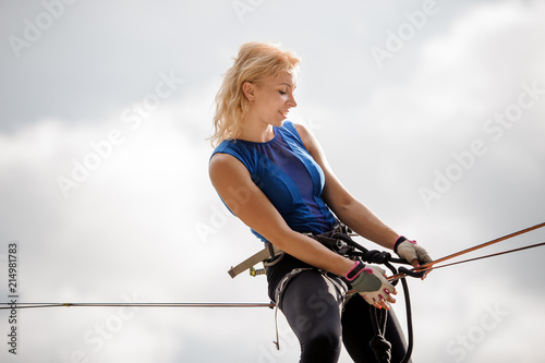Young woman sitting on the slackline rope and looking down