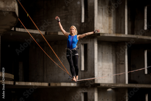 Female equilibrist balancing with arms raised on the slackline rope