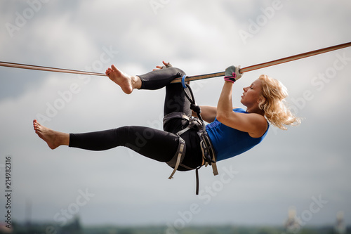 Professional female equilibrist hanging on the slackline upside down