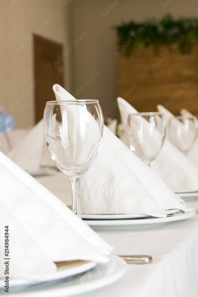 Tables set for an event party or wedding reception. luxury elegant table setting dinner in a restaurant. stylish glasses, plates on napkins and silver cutlery for guest on white table. 
