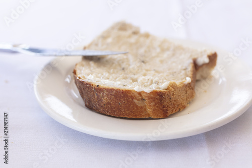 Slice of bread with a butter spread on a white plate