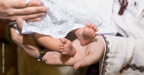 female hands hold on the legs of a small child 