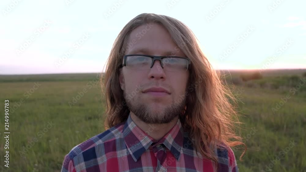 portrait of a man in glasses with long hair, quietly looking at the camera portrait of a man in glasses with long hair, quietly looking at the camera