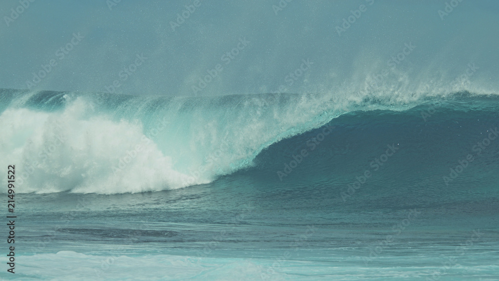 CLOSE UP: Breathtaking blue barrel wave crashing towards the tropical shore.