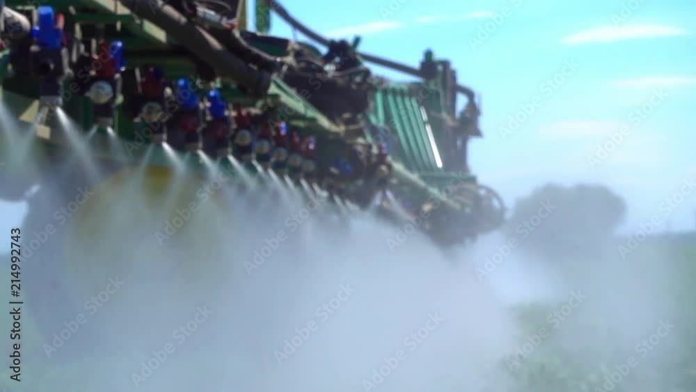 A view of the spray nozzle while working in the field. Sprayer nozzle in operation, tractor sprayer works in the field. 
