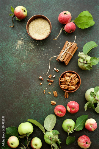 Ripe organic apples with pecans, sugar and cinnamon on dark green background.  Autumn concept
