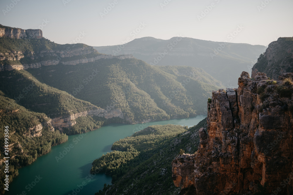Emerald river on the bottom of the beautiful ancient canyon covered with green forest on the sunset  in Spain