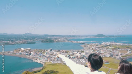 a couple is standing on the mountain of jeju island in south korea and pointing out into the view photo