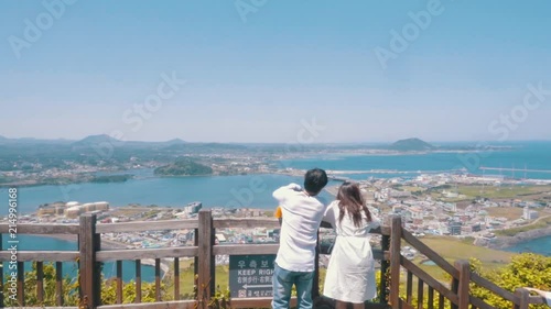 a couple is standing and pointing out over jeju island in South Korea traveling photo
