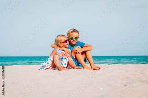 happy kids -boy and girl, brother and sister-hug on beach