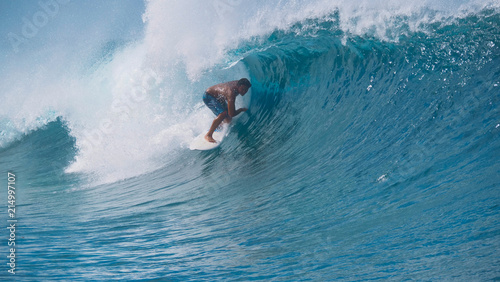 CLOSE UP Turquoise water splashes wildly behind fearless surfer riding in Tahiti