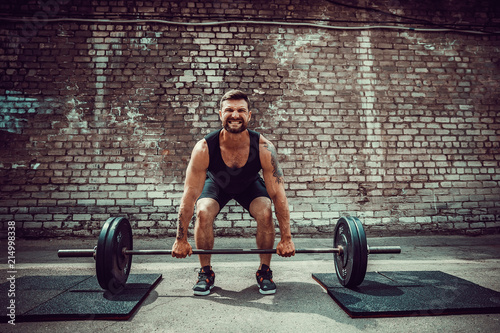 Foto Muscular fitness man doing deadlift a barbell over his head in outdoor, street gym