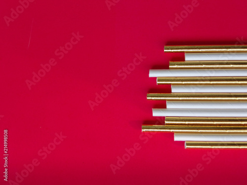 Ecological paper straw or tube for drinking  just say 'no' to plastic small and lightweight. Paper straws in white and gold colors on red background, copy space.