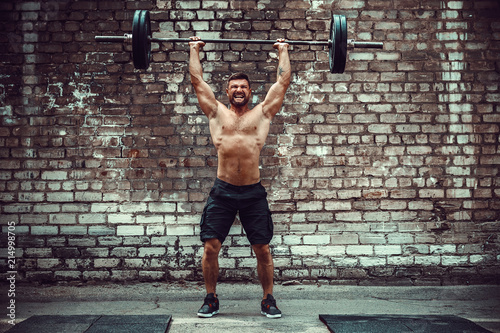 Foto Muscular fitness man doing deadlift a barbell over his head in outdoor, street gym