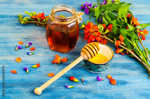 Honey from summer meadow flowers on blue wooden background photo