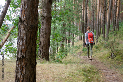 young redhead long hair woman travels in summer cloudy forest