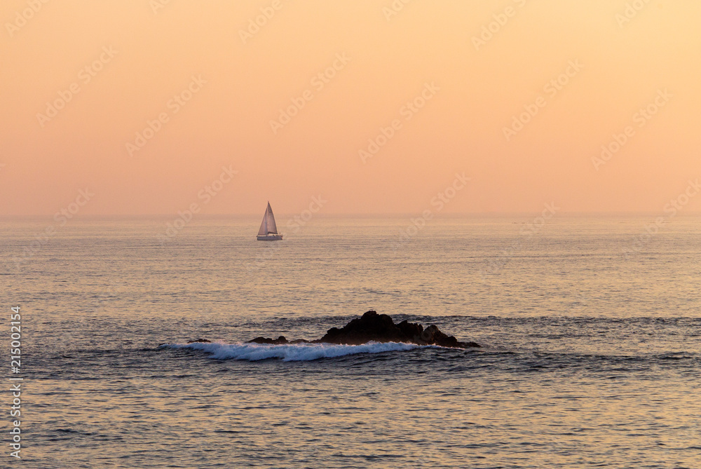 Distant Sailboat and a Rock at Sunset