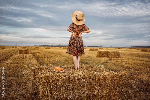Foto The girl is standing on a haystack in the field.