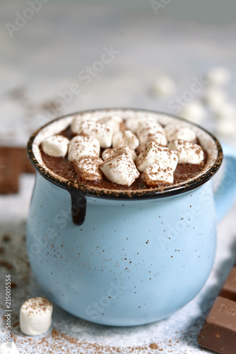 Homemade hot chocolate with mini marshmallow in a blue enamel mug.Rustic style.