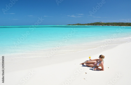 Girl with a glass of orange on the beach of Exuma, Bahamas