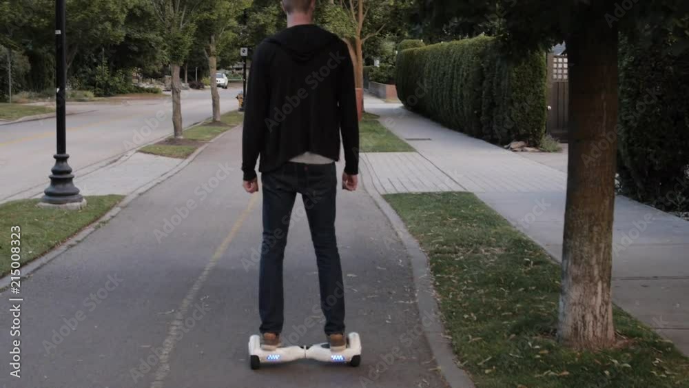Man Riding Hoverboard Along Street Man Riding Hoverboard Along Street