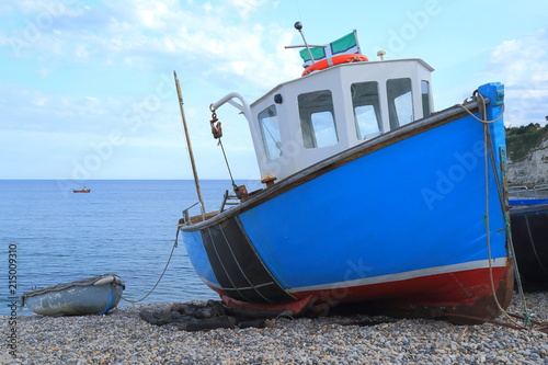 Blue fishing boat on the pebble beach near village of Beer in Devon