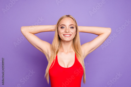 Portrait of young attractive nice gorgeous blonde smiling girl with straight hair wearing red swimsuit, relaxed, having rest on vacation trip. Isolated over violet background