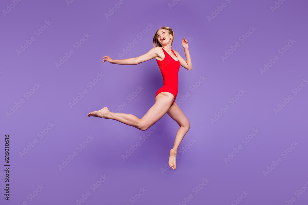 Full-size portrait of attractive young woman model with blond hair flying looking back and laughing isolated on violet background