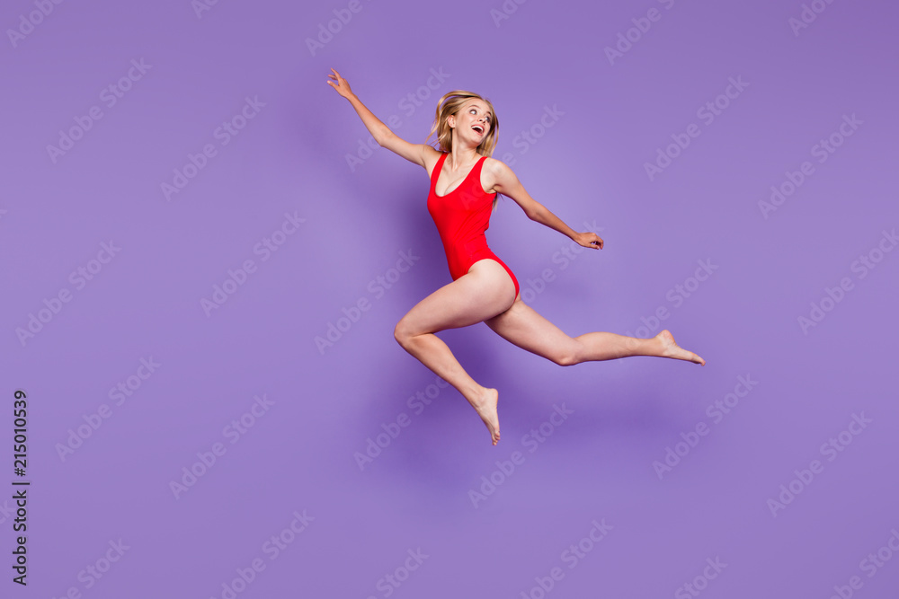 Concept of carefree summer. Full-body portrait of beautiful young female model with blond hair flying isolated on purple background