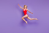 Concept of carefree summer. Full-body portrait of beautiful young female model with blond hair flying isolated on purple background