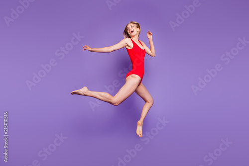 Full-size portrait of attractive young woman model with blond hair flying looking back and laughing isolated on violet background