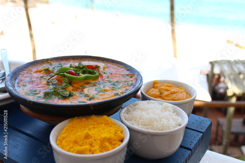 Fish moqueca, crumbs, rice, pirão and a beautiful beach in the background photo