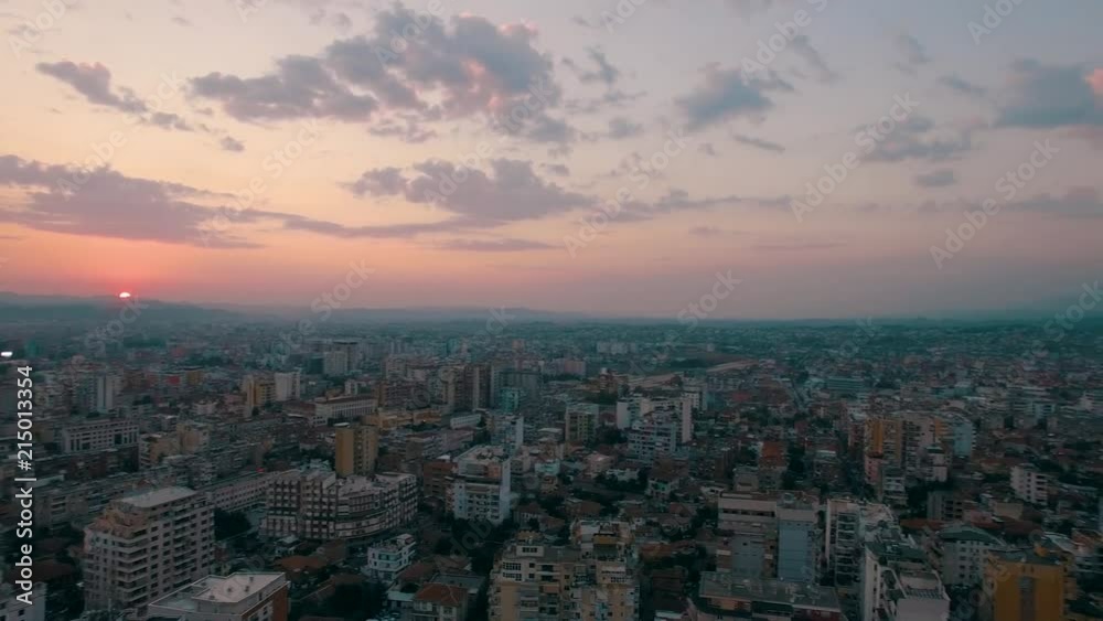 High aerial shot panning across the city of Tirana, Albania as the sun sets on the horizon High aerial shot panning across the city of Tirana, Albania as the sun sets on the horizon