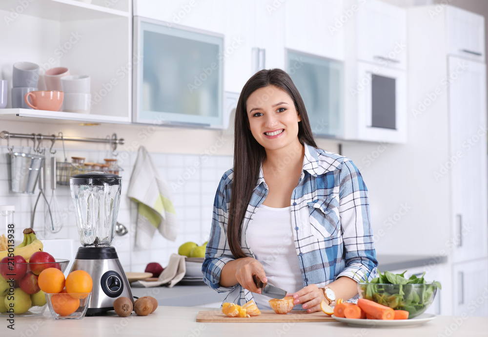 Young woman preparing tasty healthy smoothie at table in kitchen Young woman preparing tasty healthy smoothie at table in kitchen