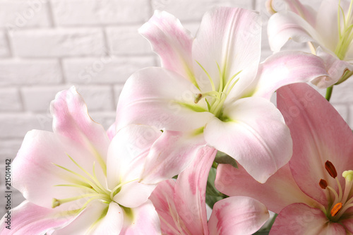 Beautiful blooming lily flowers on brick wall background © New Africa
