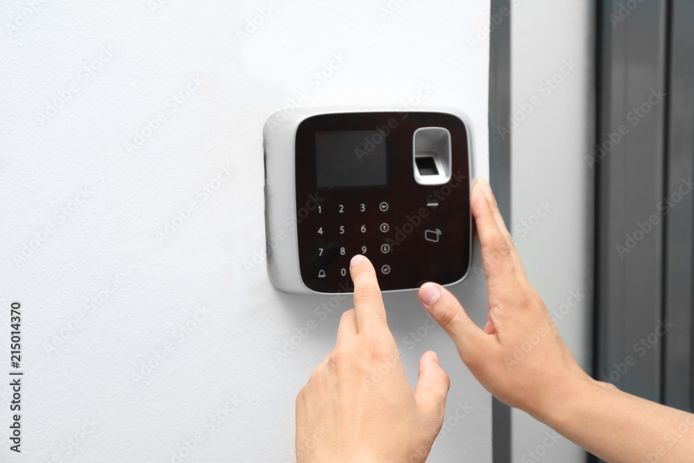 Young man entering code on alarm system keypad indoors Young man entering code on alarm system keypad indoors