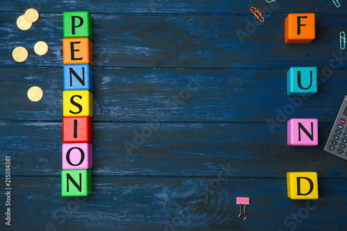 Cubes with text PENSION FUND and coins on wooden background
