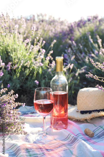Fototapeta Naklejka Na Ścianę i Meble -  Bottle and glass of wine on blanket in lavender field