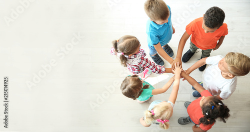 Little children putting their hands together indoors, top view. Unity concept