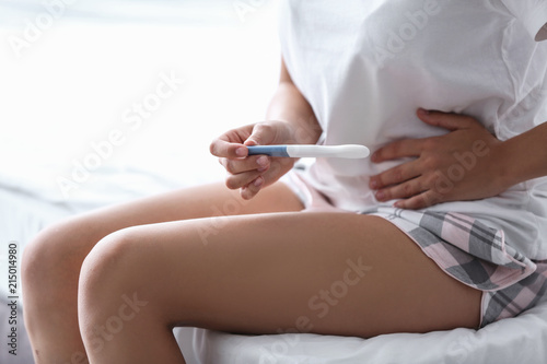 Young woman with pregnancy test in bedroom. Gynecology