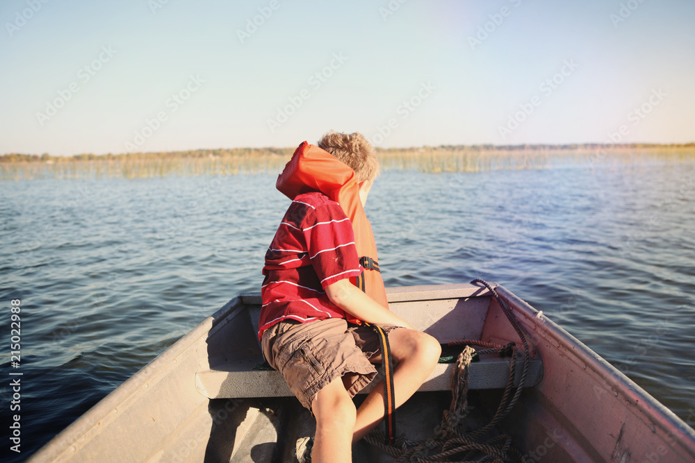 Boy wearing a life jacket in a rowboat on a lake