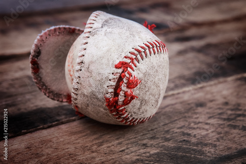 Photography Well loved baseball splitting at the seams on a wooden background