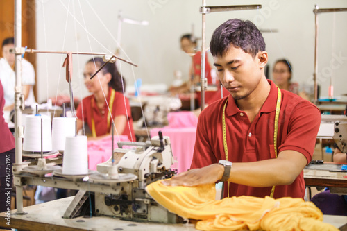 man sewing on a sewing machine at a clothing factory