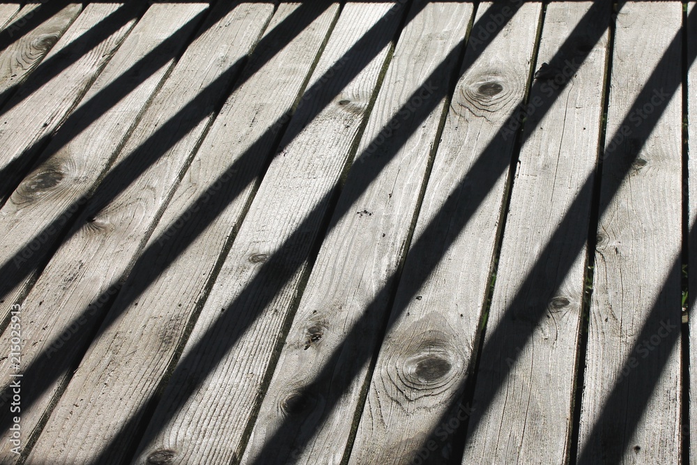 Diagonal shadows across weathered wood planks