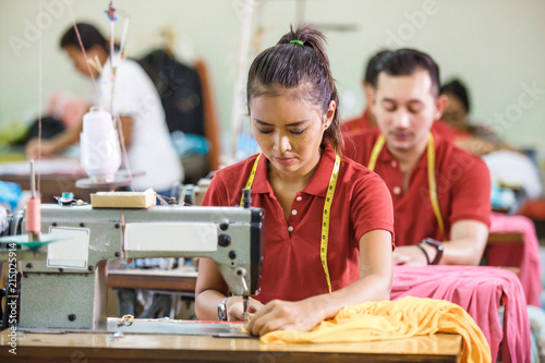 Foto Seamstress in textile factory sewing with industrial sewing mach