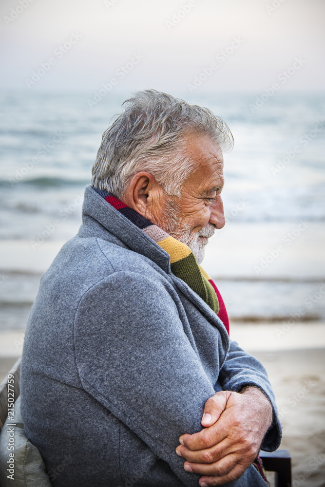 Fototapeta premium Mature man sitting on a chair by the seashore