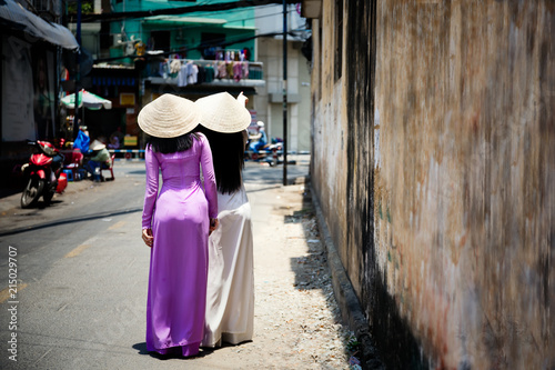 Young Vietnam woman wearing Ao Dai culture traditional walking on local street at Ho Chi Minh in Vietnam,vintage style,travel and relaxing concept.