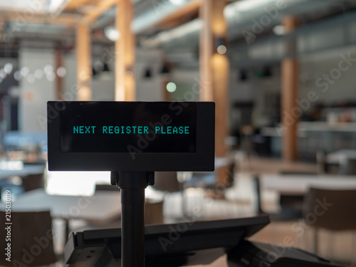 Cash register in airy eatery displaying next register please sign