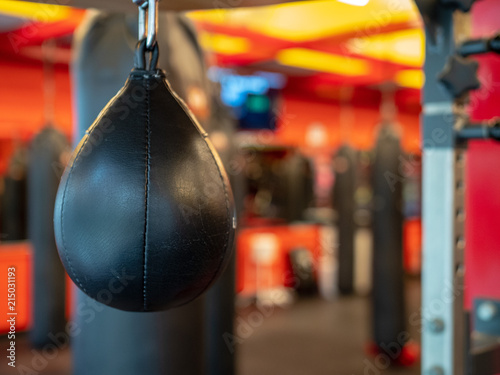 Black leather speedbag, with Muay Thai bags in the back, ready for use in a gym